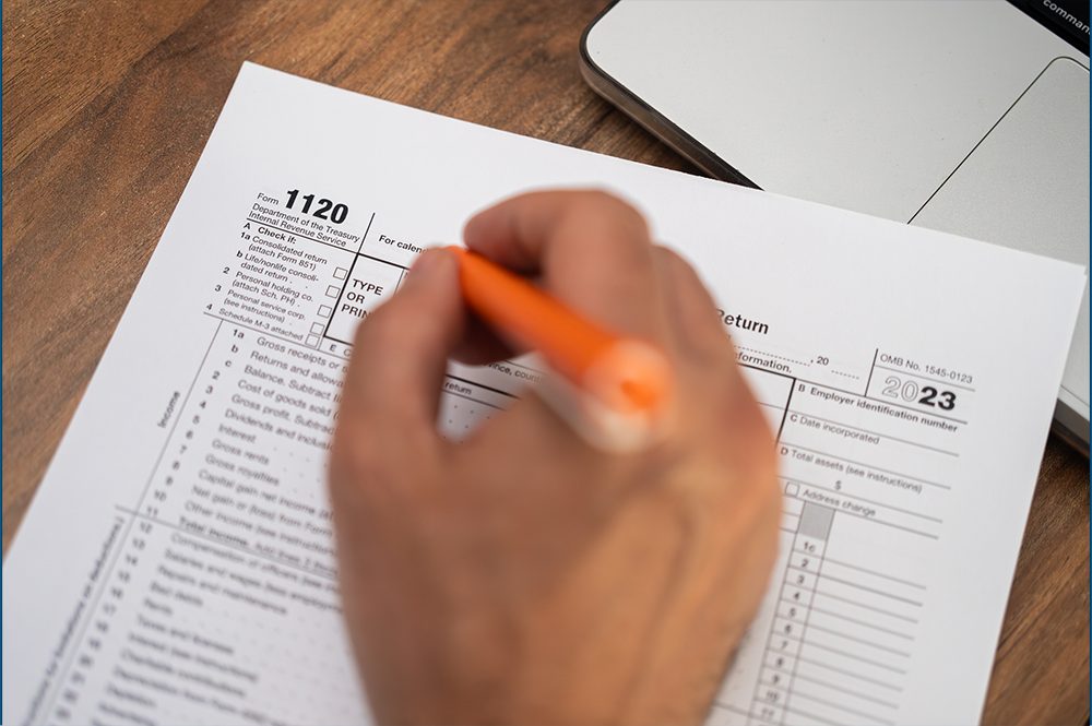 1120 form with person writing with a pen